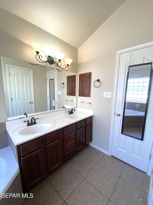 bathroom with tile patterned flooring, vanity, a chandelier, and vaulted ceiling