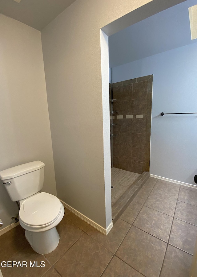 bathroom featuring tile patterned floors, toilet, and tiled shower