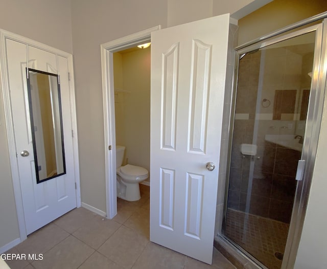 bathroom featuring tile patterned flooring, toilet, and a shower with shower door