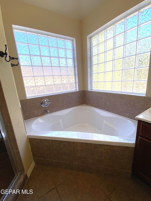 bathroom with vanity, a relaxing tiled tub, and tile patterned floors