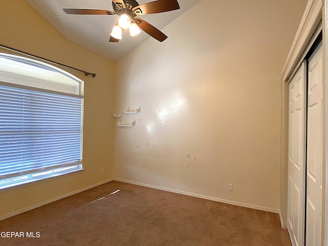 unfurnished bedroom featuring ceiling fan, a closet, carpet floors, and vaulted ceiling