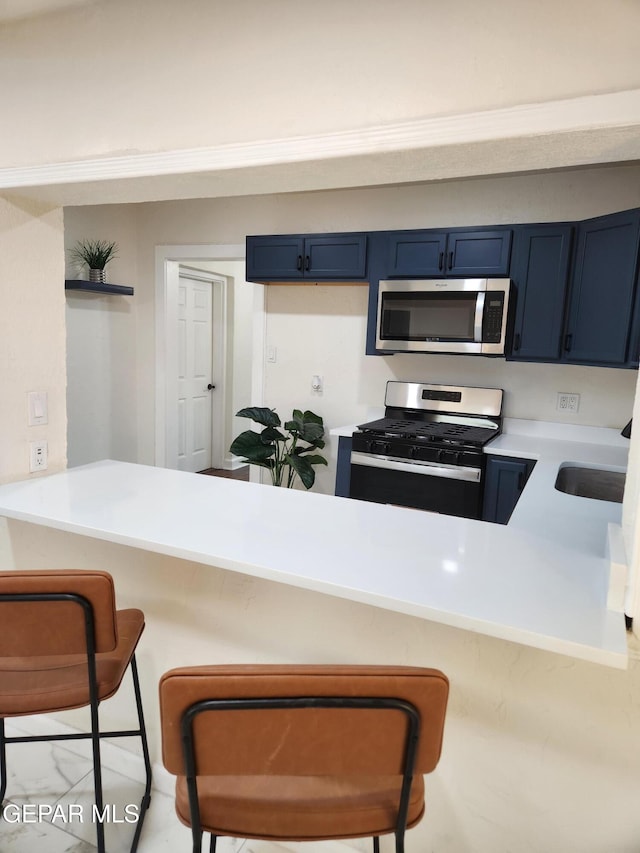 kitchen with a breakfast bar, blue cabinets, sink, kitchen peninsula, and stainless steel appliances