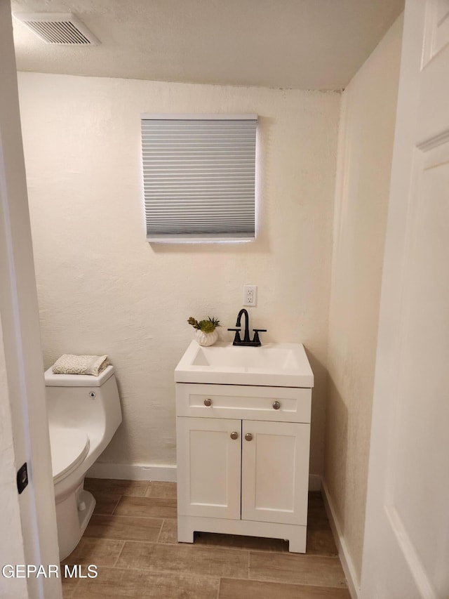 bathroom with wood-type flooring, vanity, and toilet