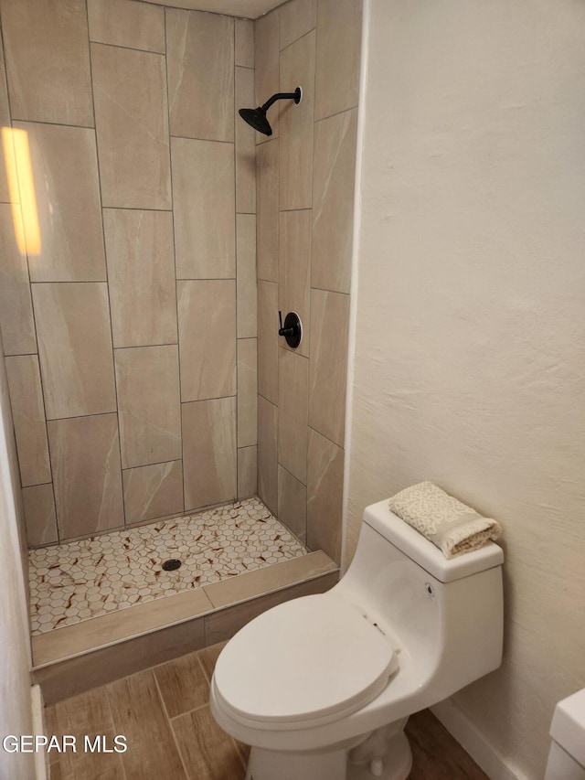 bathroom featuring toilet and a tile shower