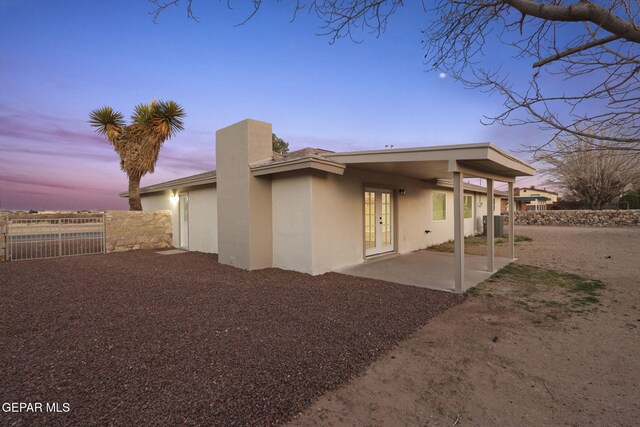 back house at dusk with a patio and french doors