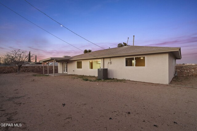 back house at dusk with central AC unit and a patio area