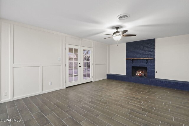 unfurnished living room with french doors, dark hardwood / wood-style floors, a brick fireplace, and ceiling fan