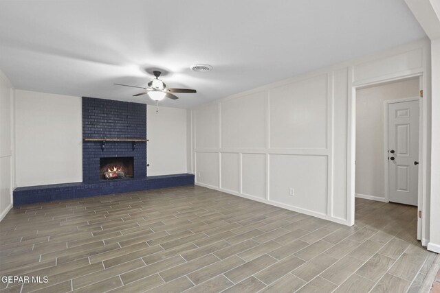 unfurnished living room featuring ceiling fan, light hardwood / wood-style floors, and a brick fireplace