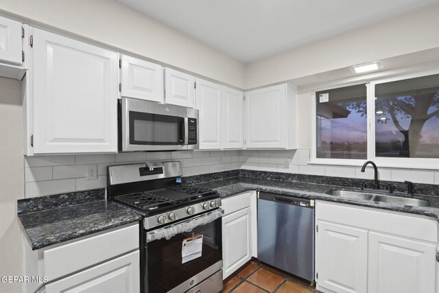 kitchen with backsplash, stainless steel appliances, white cabinetry, and sink