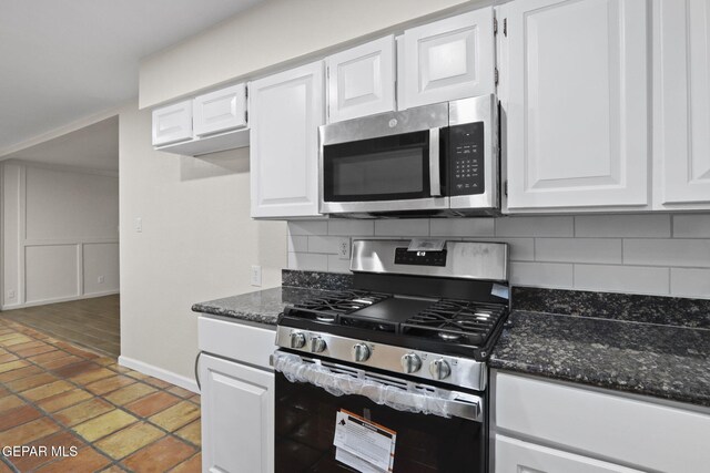 kitchen featuring white cabinets, stainless steel appliances, tasteful backsplash, and dark stone counters