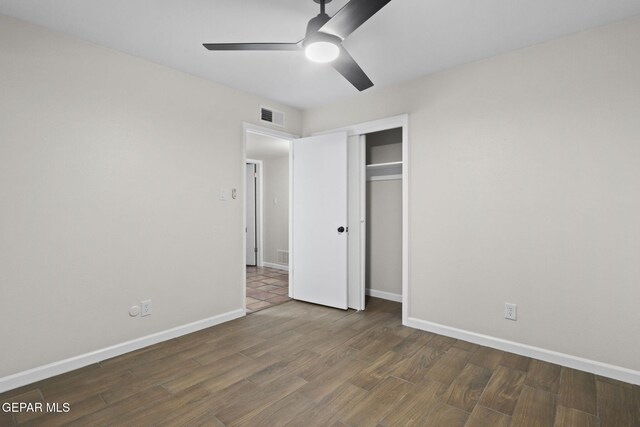 unfurnished bedroom featuring ceiling fan, a closet, and dark wood-type flooring