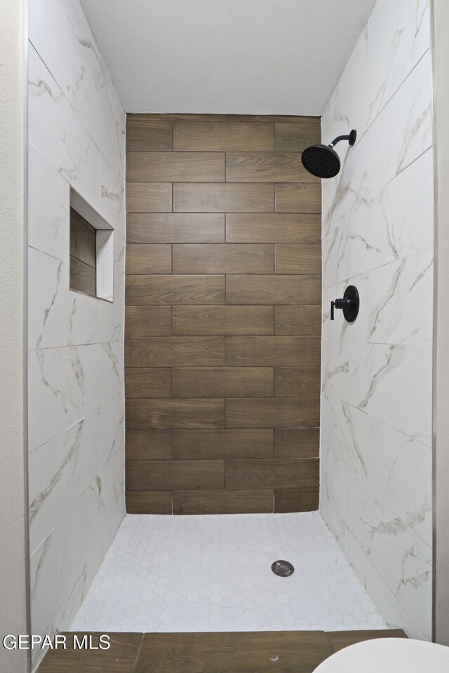 bathroom with a tile shower and toilet