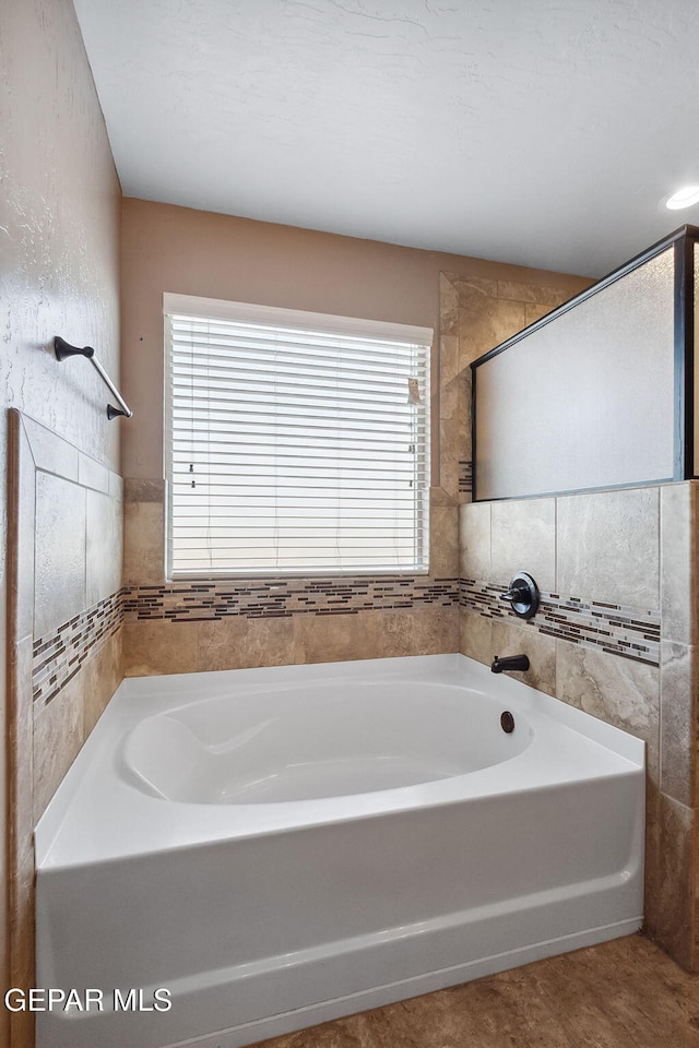 bathroom with a bathtub, tile walls, and a healthy amount of sunlight