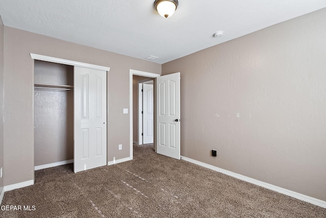 unfurnished bedroom featuring dark carpet and a closet