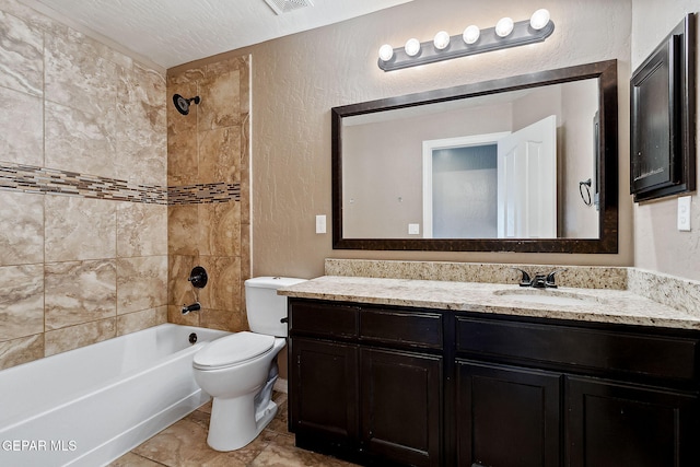 full bathroom with a textured ceiling, vanity, toilet, and tiled shower / bath