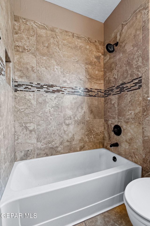 bathroom with toilet and tiled shower / bath