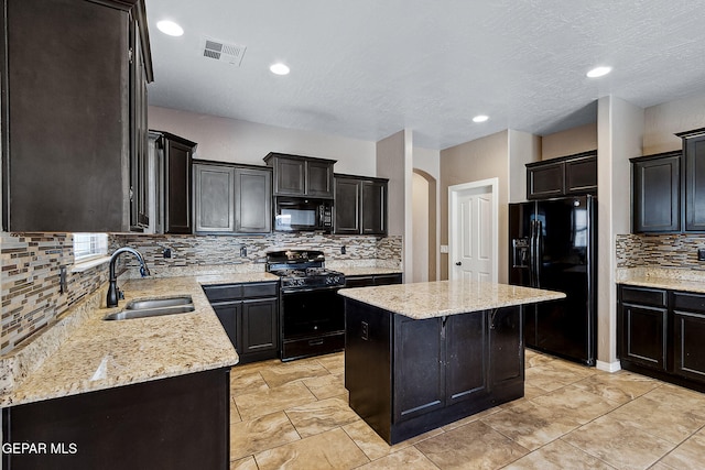 kitchen featuring light stone countertops, a center island, sink, decorative backsplash, and black appliances