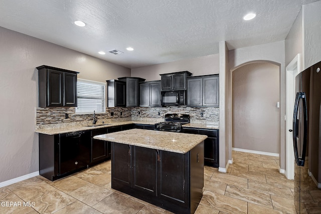 kitchen with a center island, tasteful backsplash, light stone counters, and black appliances