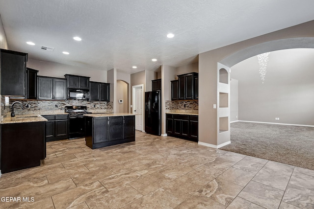 kitchen featuring black appliances, a kitchen island, light colored carpet, and backsplash