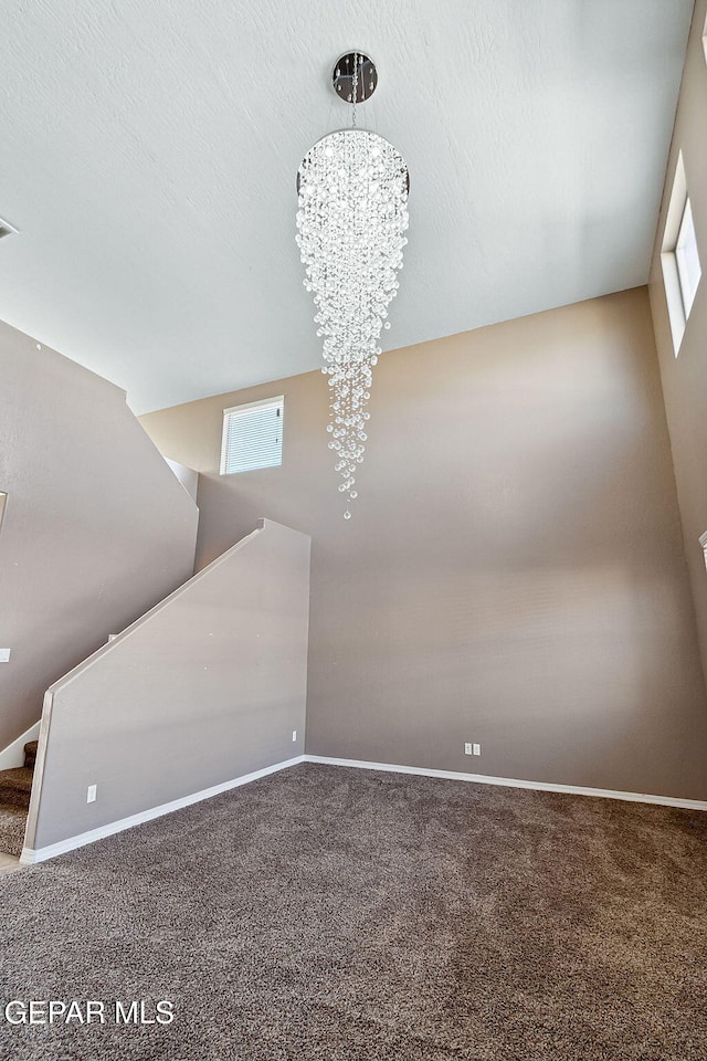 interior space featuring carpet, a textured ceiling, and an inviting chandelier