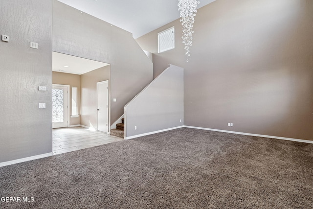 unfurnished living room featuring carpet floors and a towering ceiling