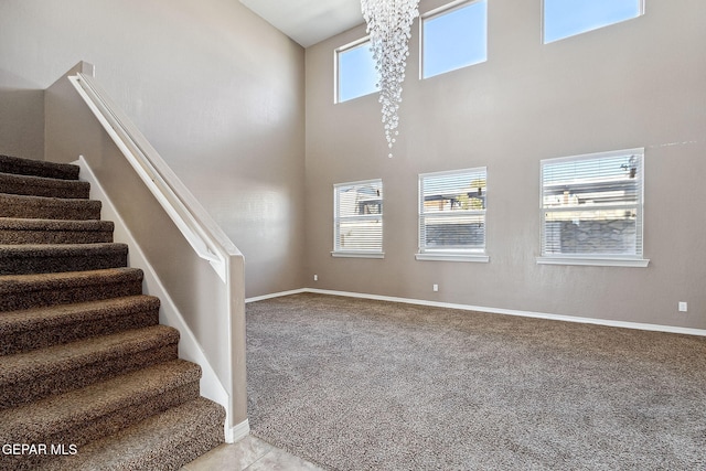 staircase featuring carpet flooring, a towering ceiling, and an inviting chandelier