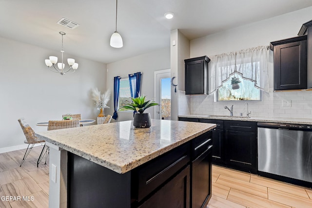 kitchen with a center island, an inviting chandelier, stainless steel dishwasher, pendant lighting, and decorative backsplash