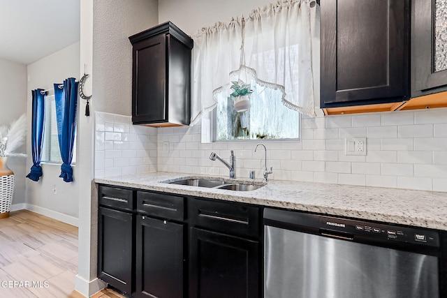 kitchen featuring stainless steel dishwasher, light stone counters, sink, and tasteful backsplash