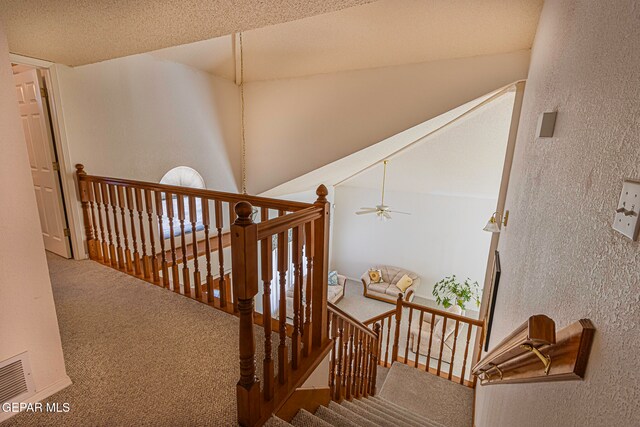 stairway with a textured ceiling, carpet floors, high vaulted ceiling, and ceiling fan