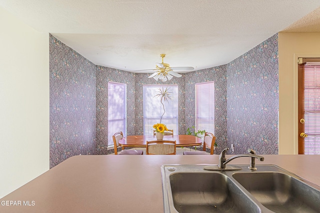 kitchen with a textured ceiling, ceiling fan, and sink