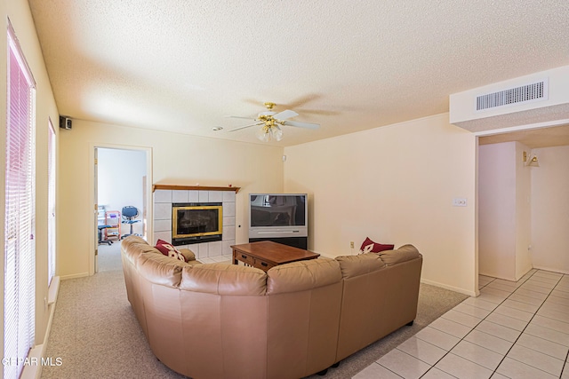 carpeted living room with a tile fireplace, a textured ceiling, ceiling fan, and a healthy amount of sunlight