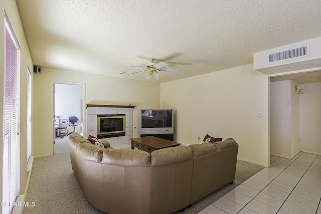 4228 Marcus Uribe Dr, El Paso, TX 79934 - living room featuring a tile fireplace, ceiling fan, a textured ceiling, light tile patterned floors, and baseboards