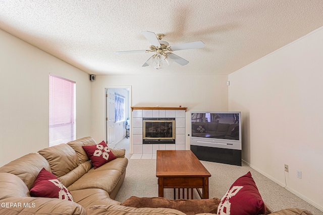 living room with light carpet, a fireplace, ceiling fan, and a textured ceiling