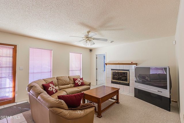 living room with a fireplace, a textured ceiling, light colored carpet, and ceiling fan