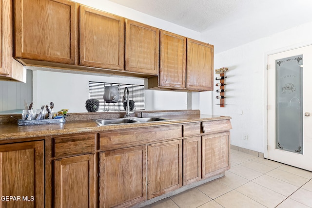 kitchen featuring a textured ceiling, light tile patterned flooring, and sink