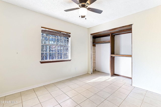 unfurnished bedroom featuring light tile patterned floors, a textured ceiling, a closet, and ceiling fan