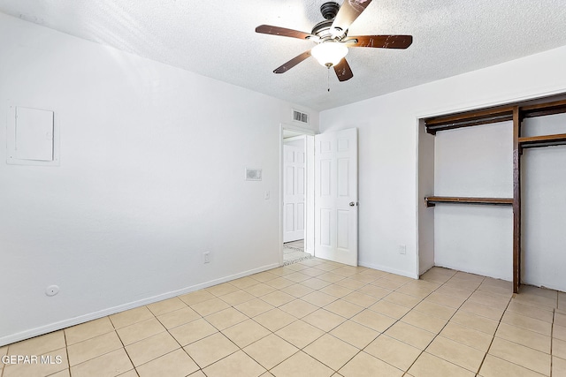 unfurnished bedroom with ceiling fan, light tile patterned floors, a textured ceiling, and a closet