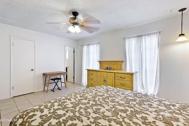 tiled bedroom with ceiling fan and a textured ceiling