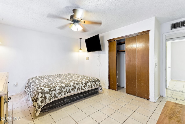 tiled bedroom featuring ceiling fan, a textured ceiling, and a closet