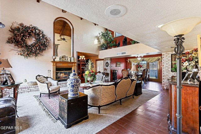 living room featuring vaulted ceiling, ceiling fan, dark wood-type flooring, and a textured ceiling