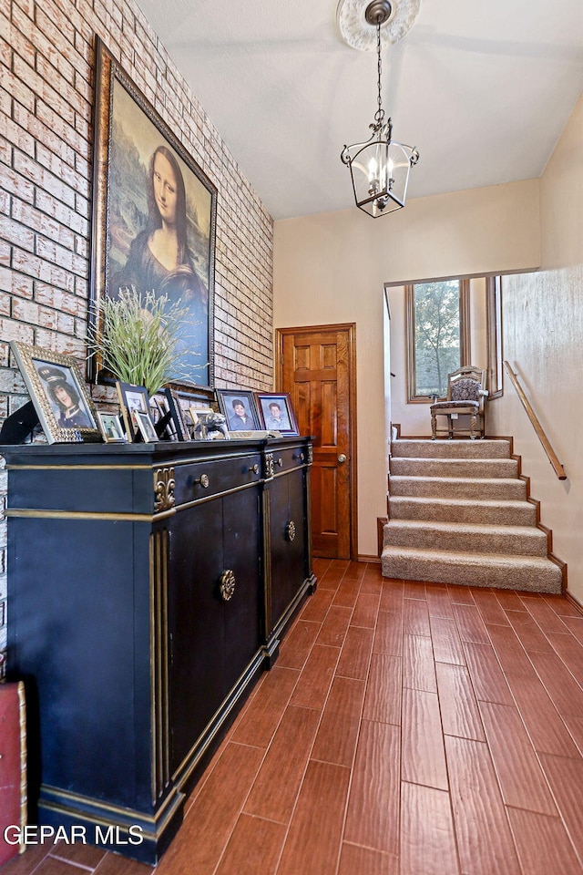 foyer entrance with an inviting chandelier and brick wall