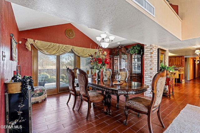 dining room featuring hardwood / wood-style floors, a textured ceiling, vaulted ceiling, and a notable chandelier