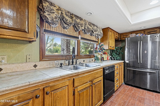 kitchen with tile countertops, stainless steel refrigerator, sink, and black dishwasher