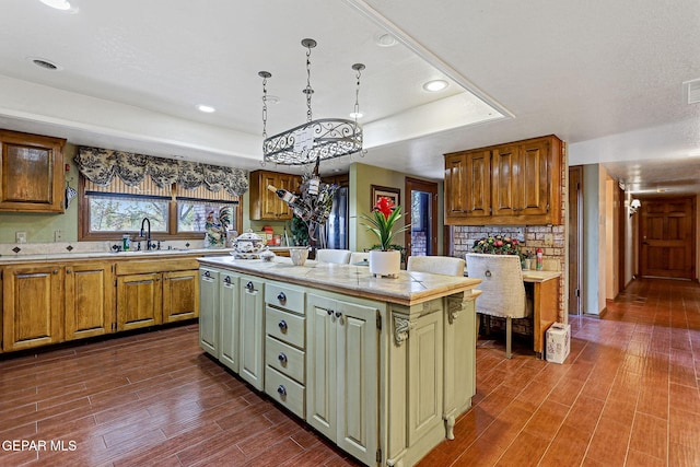 kitchen featuring a center island, sink, a raised ceiling, dark hardwood / wood-style floors, and pendant lighting