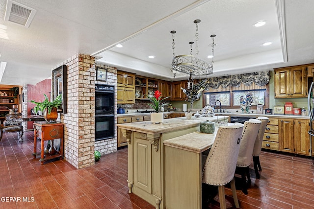 kitchen featuring a center island, dark wood-type flooring, a textured ceiling, double oven, and a tray ceiling