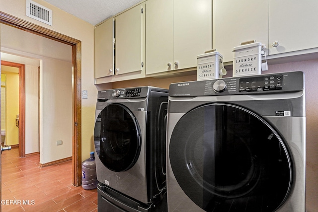 laundry area featuring light hardwood / wood-style floors, cabinets, a textured ceiling, and washing machine and clothes dryer