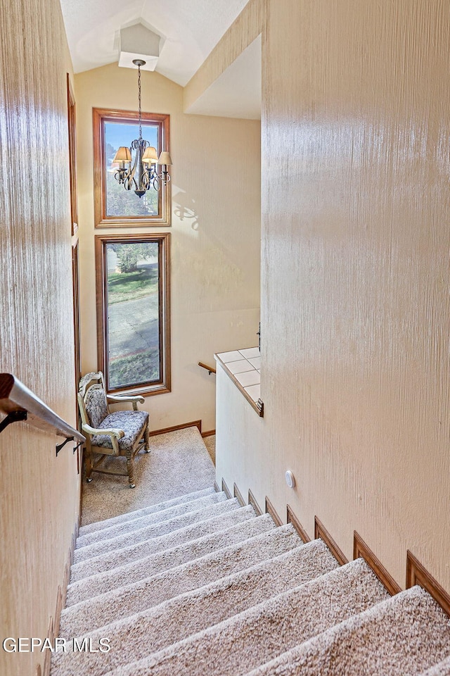 staircase featuring a chandelier, carpet, and lofted ceiling