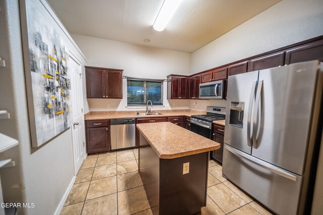 kitchen with a center island, light tile patterned floors, sink, and appliances with stainless steel finishes