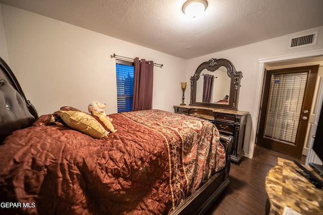 bedroom with a textured ceiling and dark hardwood / wood-style floors