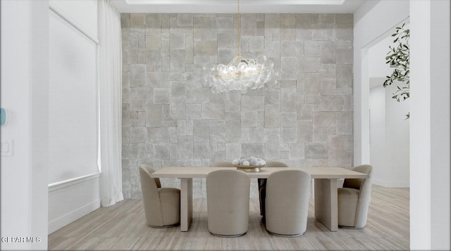 dining space featuring light wood-type flooring, an inviting chandelier, and tile walls